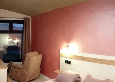 Dormitorio abuhardillado con pared roja y sillón
